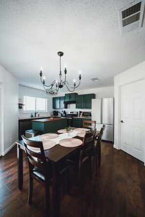 A spacious kitchen with a dining area, featuring a chandelier, green cabinets, and a white door. - Lovely 3br/2.5ba Home Six Flags/La Cantera/USAA/UTSA (San Antonio)