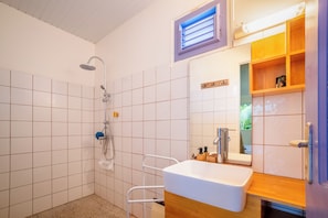 A bathroom with a shower, a sink, and a mirror. - New Listing (Saint-Pierre)