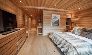A wooden cabin interior with a bed, a desk, and a chair. - PREMIUM ALPINE RESIDENCE WITH DESIGNER KITCHEN AND HOTEL SPA ACCESS (Zermatt)