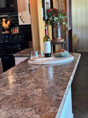 A kitchen counter with a wine bottle, glasses, and a decorative item. - Whidbey Island Water View Oasis with Hot Tub. (Freeland)
