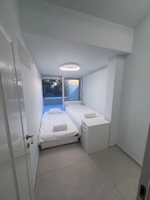 Ein kleines, modernes Schlafzimmer mit einem Bett, einem Schreibtisch und einem Fenster.