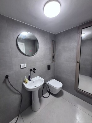 Ein Badezimmer mit einem Waschbecken auf Säule, einer Toilette, einem Spiegel und einer Duschkabine.