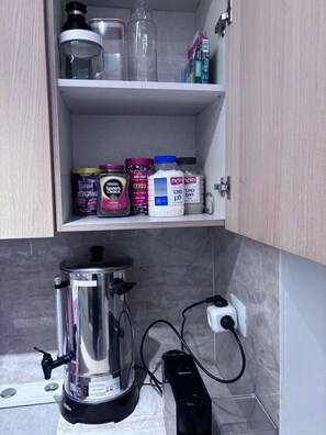 Eine Küche mit Kaffeemaschine, Mixer und verschiedenen Lebensmitteln in den Regalen.