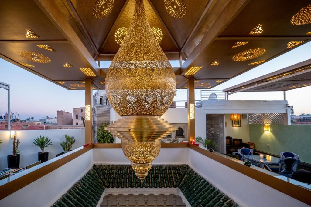 A rooftop terrace with a large ornate hanging light fixture, potted plants, and a seating area.