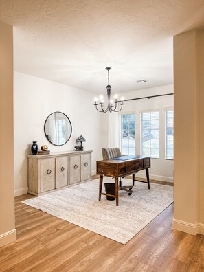 A spacious room with a wooden desk, a chandelier, a mirror, and a cabinet. - Charming House in Little Valley (St. George)
