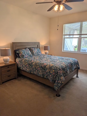Quarto com cama, mesas de cabeceira, luminárias, ventilador de teto e janela com persianas.