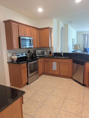 A kitchen with wooden cabinets, a microwave, a toaster, a stove, and a dishwasher. - Pelican Preserve-Fort Myers - Top 55 + active --2 bdrm 2 bath Villa turn key (Fort Myers)