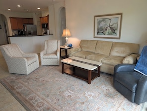 A living room with a sofa, two armchairs, a coffee table, and a rug. - Pelican Preserve-Fort Myers - Top 55 + active --2 bdrm 2 bath Villa turn key (Fort Myers)