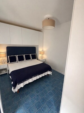 A bedroom with a bed, nightstands, a ceiling lamp, and a blue tiled floor. - New Listing (Palermo)