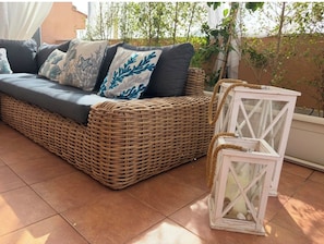A wicker sofa with cushions, a white lantern, and a tiled floor. - New Listing (Palermo)