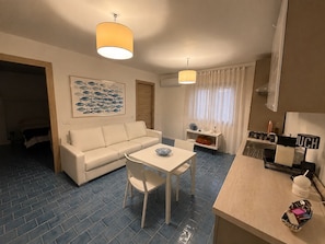 A modern living room with a sofa, a dining table, and a kitchen area with a stove and sink. - New Listing (Palermo)
