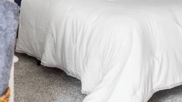Un dormitorio con cama, almohadas, una mesita de noche y una lámpara.