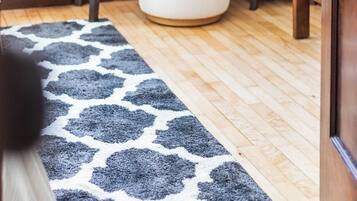 Una habitación con un escritorio de madera, un reposapiés blanco y una alfombra estampada.