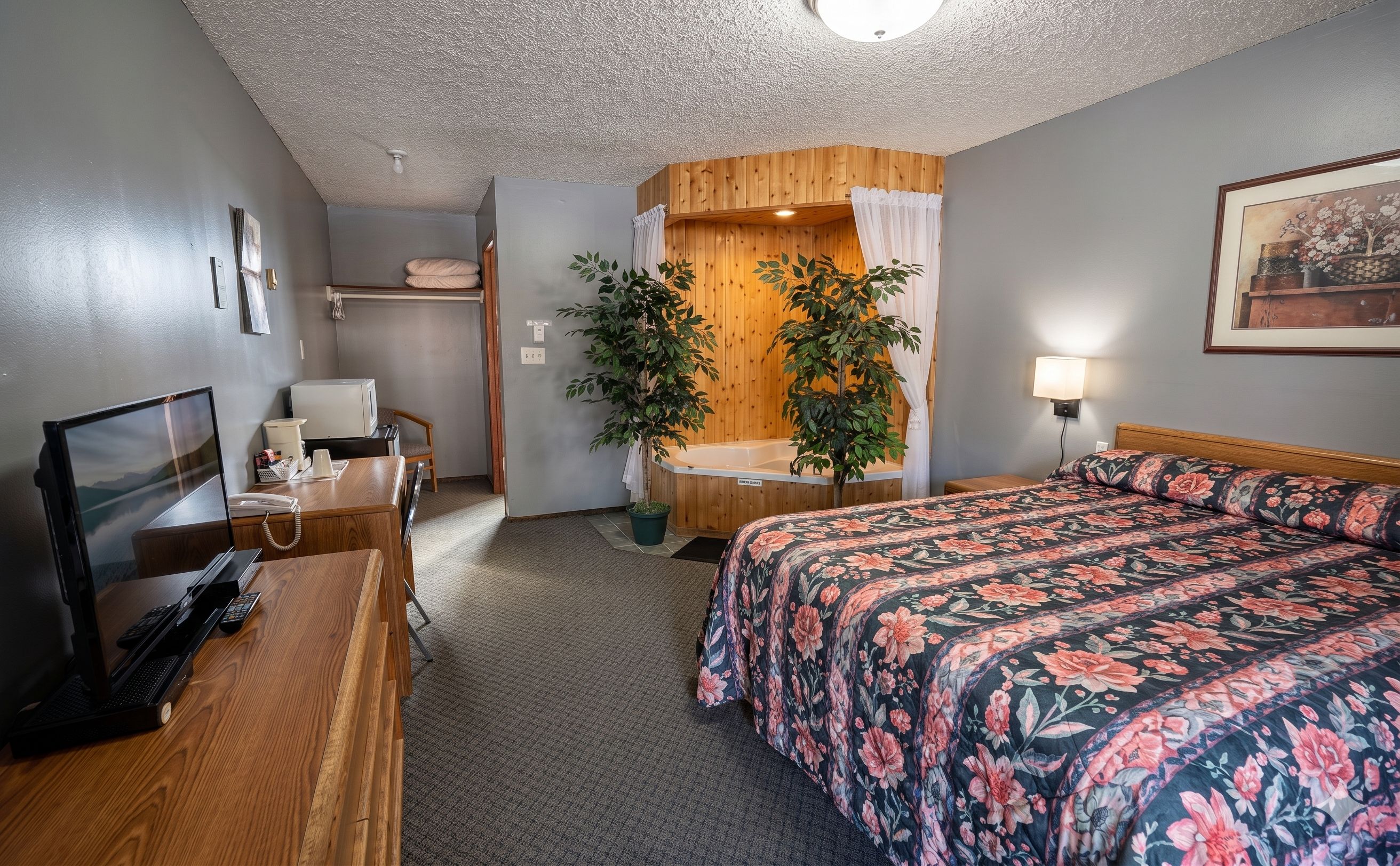 A hotel room with a bed, desk, chair, and a small bathroom area.