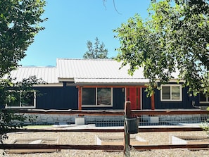 A building with a red door, large windows, and a metal roof. - Cozy Reno/Tahoe 3-bedroom House - Pet Friendly! (Reno)