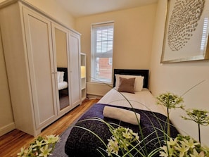 A bedroom with a bed, a wardrobe, a window, and a wall-mounted artwork. - Spacious, Spacious & Modern Apt w/ Free Parking (Coventry)