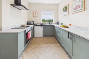 A modern kitchen with a dishwasher, a window, and a view of the outdoors. - 4 Bed House with Garden - Perfect for Contractors and Families (Allerton Bywater)