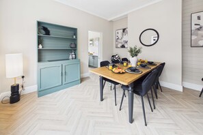 A dining area with a wooden table set for four, surrounded by chairs. - 4 Bed House with Garden - Perfect for Contractors and Families (Allerton Bywater)