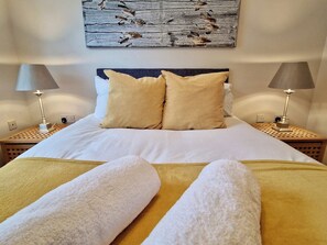A neatly made bed with white and yellow linens, two bedside lamps, and a wall-mounted artwork above. - Spacious & Spacious Apt w/ Study | Free Parking (Coventry)