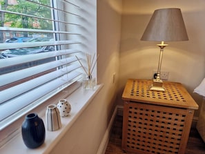 A corner with a window, a lamp, and a small wooden table with a grid pattern. - Spacious & Spacious Apt w/ Study | Free Parking (Coventry)