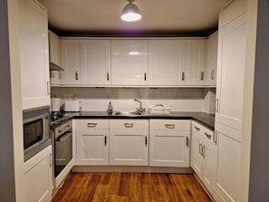 Cozinha com armários brancos, micro-ondas, forno e pia.