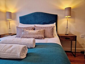 A neatly made bed with a teal bedspread, white pillows, and two rolled towels. - Stylish Apt in Trendy Earlsdon, Free Parking (Coventry)