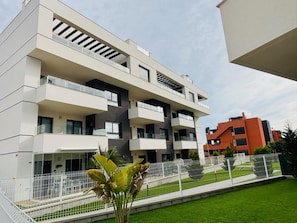 A multi-story residential building with balconies, a gated entrance, and a well-maintained lawn. - Apartment Valentino Golf Villamartin (Orihuela)