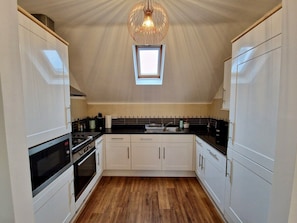 A compact kitchen with white cabinets, a black countertop, and a skylight above. - Trendy Condo Near City Centre w/ Free Parking (Coventry)