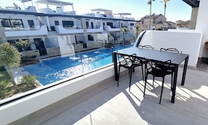 A rooftop terrace with a pool, outdoor seating, and a view of modern buildings. - Penthouse Innovabeach Punta Prima (Orihuela)