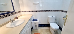 Un baño con lavamanos, inodoro y perchero para toallas.