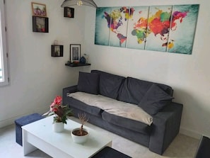 A living room with a grey sofa, a white coffee table, and a world map artwork on the wall. - New Listing (Montpellier)
