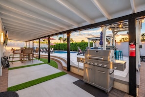 Eine Außenpatio mit Grill, Sitzgruppe und Pool.