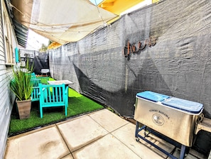 Eine Terrasse mit Tisch und Stühlen, einem Grill und einer Wand mit dem Schriftzug 'house'.