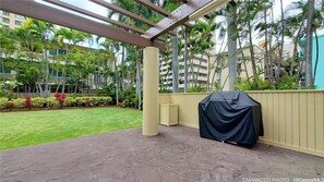 A covered outdoor area with a grill, a small trash bin, and a well-maintained lawn. - Rare find. Spacious 1bdrm OV with panoramic views. (Honolulu)