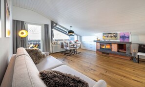 Ein modernes Wohnzimmer mit Kamin, Holzboden und einer Couch mit flauschigem Überwurf.