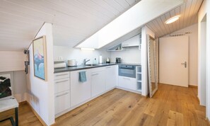 Eine moderne Küche mit weißen Schränken, Holzboden und einem Oberlicht.