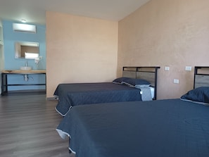 Et hotelværelse med to senge, et håndvask og et spejl.