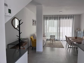 Un espacio habitable moderno con comedor, un sofá, una mesa de centro y una mesa de comedor con sillas.