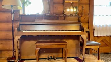 A wooden interior with a grand piano, a small table, a chair, and a lamp.