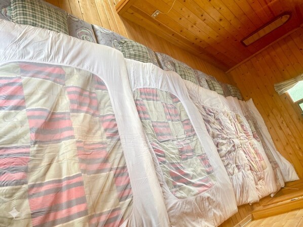 A bed with multiple pillows and a blanket in a wooden cabin room.