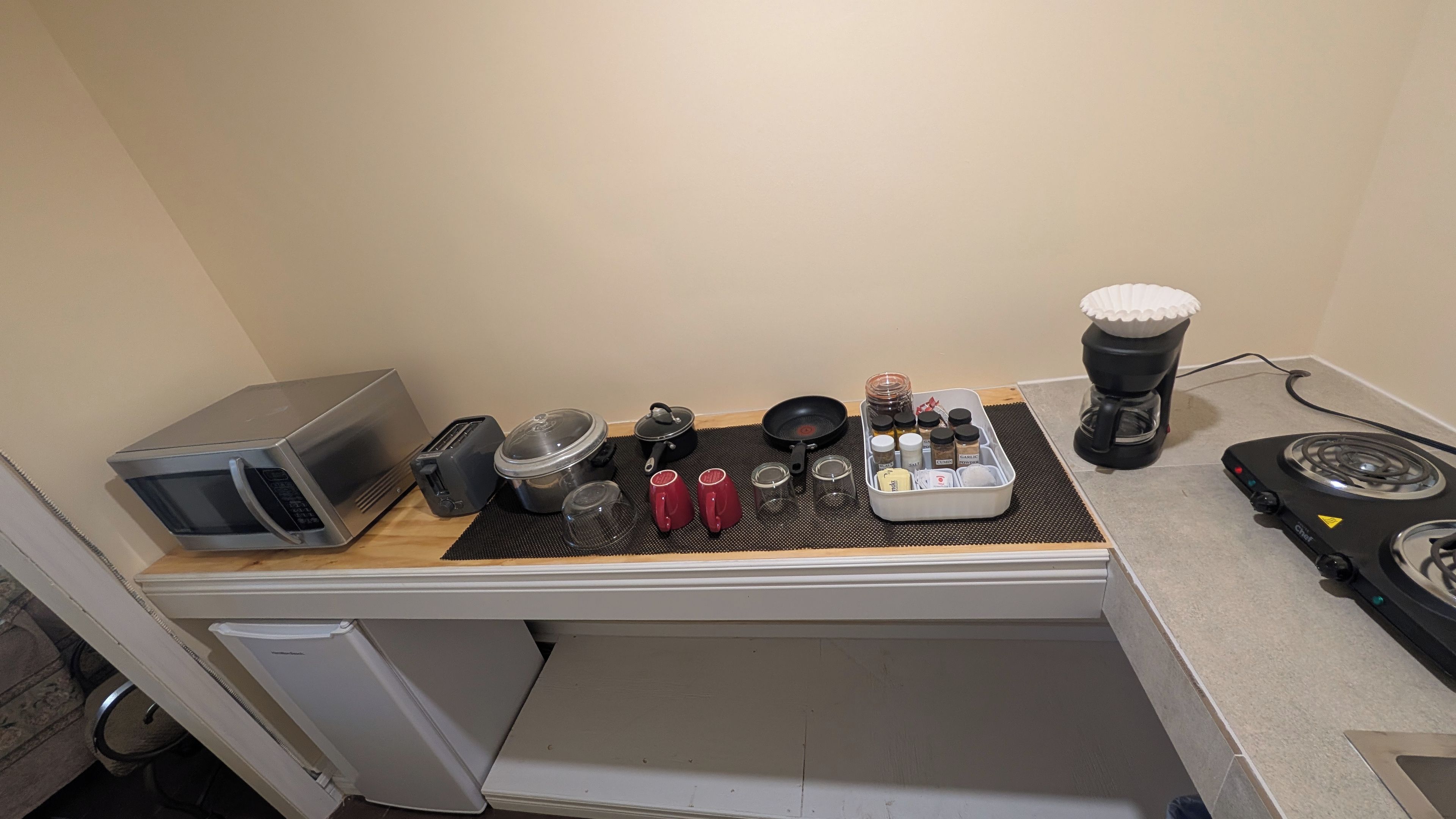 A kitchenette with a microwave, toaster, kettle, coffee maker, and a gas stove.
