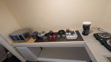 A kitchenette with a microwave, toaster, kettle, coffee maker, and a gas stove.
