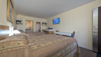 Quarto de hotel com cama grande, escrivaninha, televisão e banheiro visível por uma porta aberta.