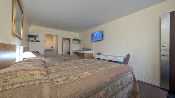 Quarto de hotel com cama grande, escrivaninha, televisão e banheiro visível por uma porta aberta.