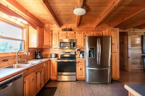 A modern kitchen with wooden cabinets, stainless steel appliances, and a large refrigerator. - Comfy 4-bedroom cabin with picturesque views, near Pigeon Forge and Gatlinburg (Sevierville)