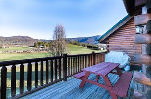 A wooden deck with a picnic table and a view of a green landscape with hills. - Comfy 4-bedroom cabin with picturesque views, near Pigeon Forge and Gatlinburg (Sevierville)