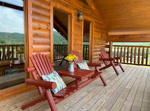 A wooden deck with two Adirondack chairs and a vase of yellow flowers. - Comfy 4-bedroom cabin with picturesque views, near Pigeon Forge and Gatlinburg (Sevierville)