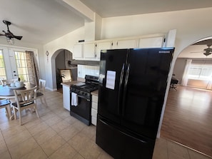 A kitchen with a black refrigerator, a stove, and a dining table with chairs. - 3-bedroom, King bed in spacious condo (Wildomar)