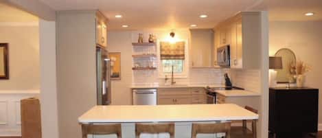 A kitchen with a central island, bar stools, and built-in appliances.