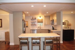 Una cocina con una isla central, taburetes de bar y electrodomésticos integrados.
